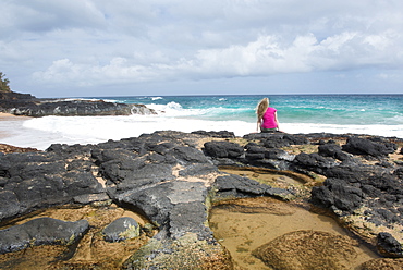 Sitting by a tidal pool on Secret Beach on the Hawaiian island of Kauai, Hawaii, United States of America, North America