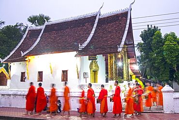 Buddhist monks receive rice from locals during an early morning daily ritual known as Sai Bat (morning alms) in Luang Prabang, Laos, Indochina, Southeast Asia, Asia