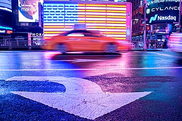 Taxi blurring by an illuminated flag of the United States of America at Times Square, New York City, United States of America, North America