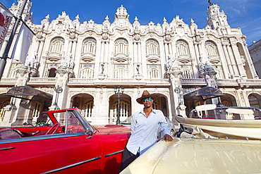 Taxi driver next to his vintage car in front of the Gran Teatro de La Habana, Havana, Cuba, West Indies, Caribbean, Central America