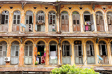 The first and second floors of an old colonial apartment building in Chinatown, showing archways and wooden doors, Yangon (Rangoon), Myanmar (Burma), Asia