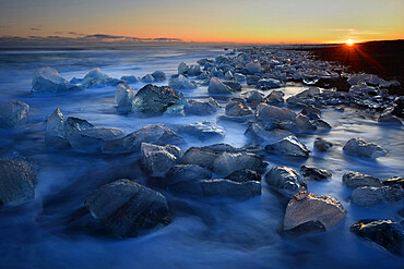 Pieces of glacial ice over black sand being washed by waves, Iceland, Polar Regions