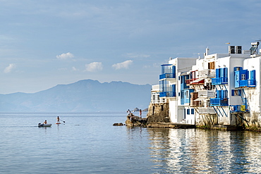 Paddle Boarder, inflatable boat and tourists on rock in Mykonos Town, Mykonos, Cyclades, Greek Islands, Greece, Europe