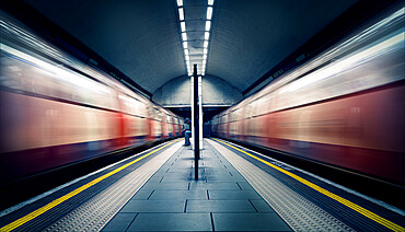 Two trains in motion and a seated commuter at London Tube Station, Clapham Common, Clapham, London, England, United Kingdom, Europe