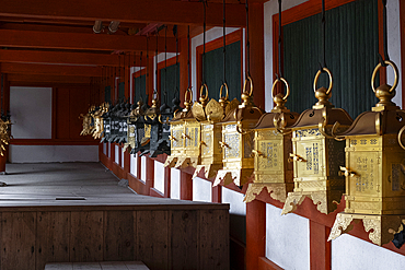 A row of lanterns in vibrant golden colors hang gracefully from a portico of a temple in Nara, Honshu, Japan, Asia