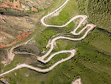 Aerial view of a winding mountain road curves, Kalmak Ashuu Pass, through lush greenery in Kyrgyzstan, Central Asia, Asia