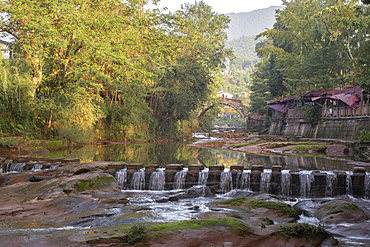 The famous ancient arch stone bridge in Shangli Town at sunrise with some small waterfall in the river