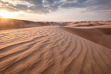 Sand dunes at sunset in the Wahiba Sands desert with clouds in the sky, Oman, Middle East