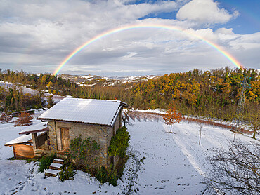 Rainbow arch above a small cottage and a snowy winter countryside landscape, Emilia Romagna, Italy, Europe