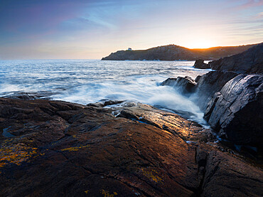 Sunrise over a bay with waves coming through the camera, Brittany, France, Europe