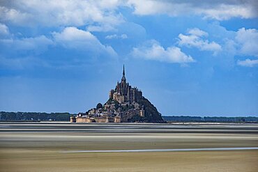 Le Mont Saint Michel with low tide in a sunny day with some white clouds, Normandy, France