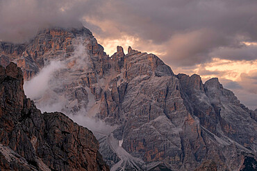 Sunset light above Tofane with some low clouds hanging between rocks, Dolomites, Italy, Europe