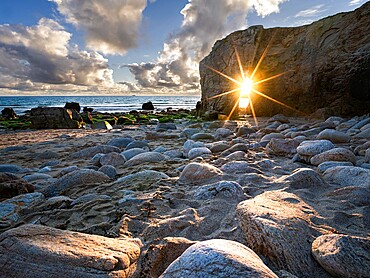 Sun burst aligned with the natural arch of Port Blanc, Quiberon, Brittany, France, Europe