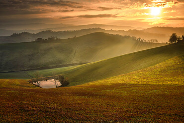 Sunset over Italian countryside and hills with a small lake, Italy, Europe