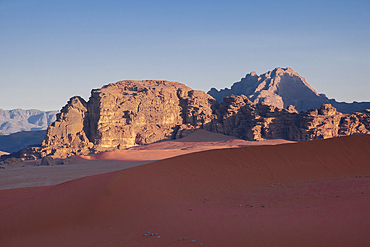 Morning light on mountains over the red sand dune of Wadi Rum