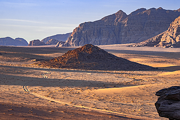 Wadi Rum plain at sunrise with soft light over the sand dunes and mountains