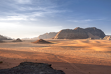 Wadi Rum plain at sunrise with soft light over the sand dunes and mountains