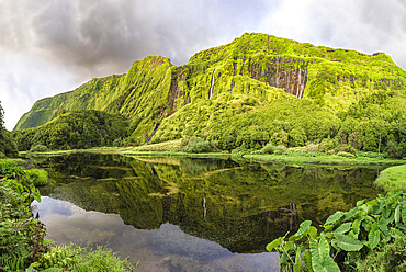 Panorama shot of Poco da Ribeira do Ferreiro lake and waterfall with a side of the mountains covered by flowers and vegetation, Flores island, Azores Islands, Portugal, Atlantic Ocean, Europe