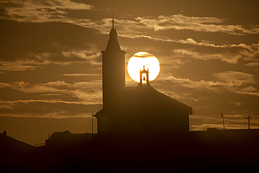 Sun aligned with the silhouette of the church of Luarca, Asturias, Spain, Europe