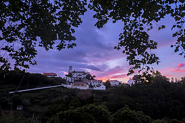 Sunset colors over Santo Antonio de Nordestinho framed by tree branches, Sao Miguel Island, Azores Islands, Portugal, Atlantic, Europe