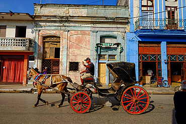 A horse-drawn carriage driver waves as he passes by, Cardenas, Matanzas, Cuba, West Indies, Central America