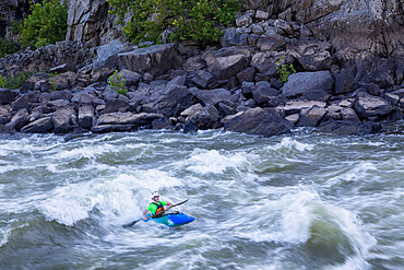 A kayaker surfs big standing waves of the Potomac River near Great Falls in his whitewater boat, Virginia, United States of America, North America