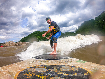 Photographer Skip Brown stand up paddle surfs a challenging whitewater wave on the Potomac River, Maryland, United States of America, North America