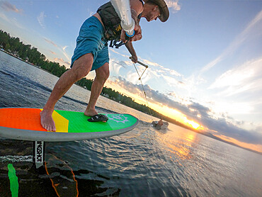 Photographer Skip Brown foils behind a small boat at sunset on Sebago Lake, Maine, United States of America, North America