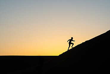 Silhouette of a man running up a sand dune in Nags Head, North Carolina United States of America, North America