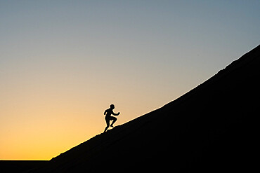 Silhouette of a man running up a sand dune in Nags Head, North Carolina, United States of America, North America