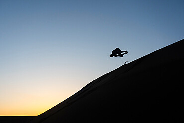 Silhouette of a man tumbling down a sand dune in Nags Head, North Carolina, United States of America, North America