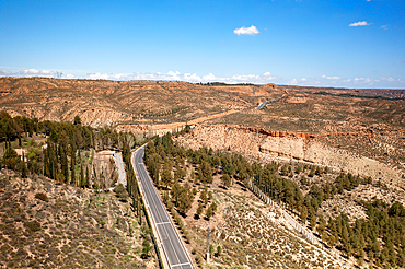 Drone aerial view of a road crossing a desert like landscape near Francisco Abellan Dam and Reservoir, Granada, Andalusia, Spain, Europe