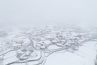 Drone aerial view of a road and remote village covered with snow in Vila Real, Norte, Portugal, Europe