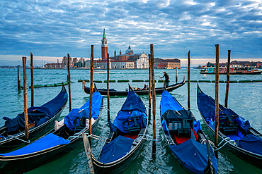 Gondolier paddling a gondola with San Giorgio Maggiore island and Basilica in the background at sunset, Venice, UNESCO World Heritage Site, Veneto, Italy, Europe