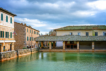 Bagno Vignoni hot springs pool with traditional Tuscany buildings, in Italy