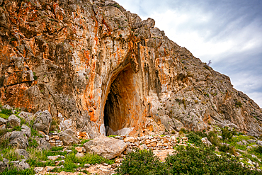 Cave of Elafonisos island with orange rock color painted in white, in Greece