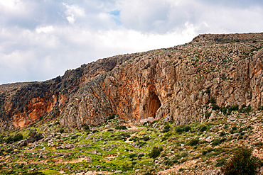 Cave of Elafonisos island with orange rock color painted in white, in Greece