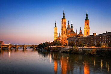 Basilica del Pilar Cathedral with stone bridge crossing Ebro River at sunset, Zaragoza, Aragon, Spain, Europe