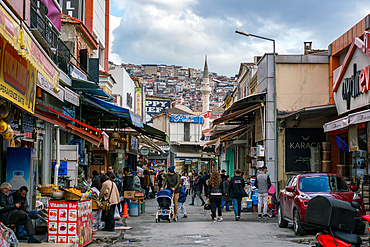 Street in Izmir full with shops with a Minaret tower of a mosque in Turkey