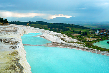 Pamukkale calcium carbonate white travertines with turquoise water on a cloudy day in Turkey