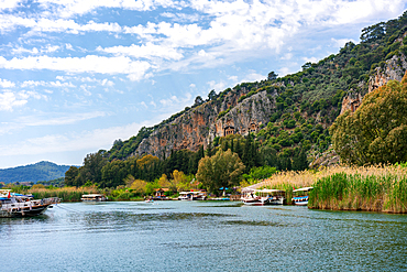 Tourist boats in Dalyan bay with Tombs of the kings carved on the hills in Turkey