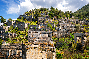 Kayakoy greek ghost town with abandoned houses in the mountains full of vegetations in Fethiye, Turkey