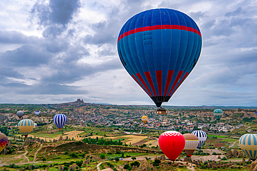 Hot air balloons in Cappadocia with Ortahisar city in the background at sunrise in Turkey