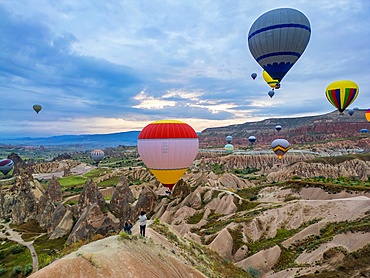 Drone aerial view of tourists looking at hot air balloons flying over Cappadocia in Turkey at sunrise