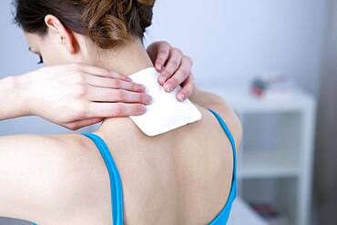 Woman applying heat patch.