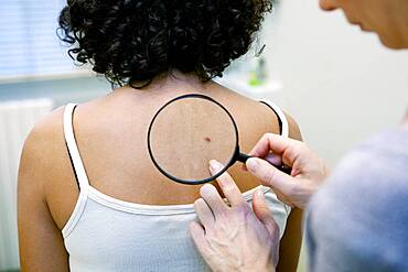 Dermatologist examining patient's moles.