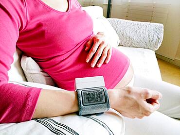 Pregnant woman measuring her blood pressure.