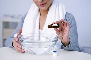 Woman preparing inhalation with essential oil.