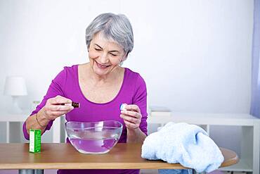 Senior woman preparing inhalation with essential oil.