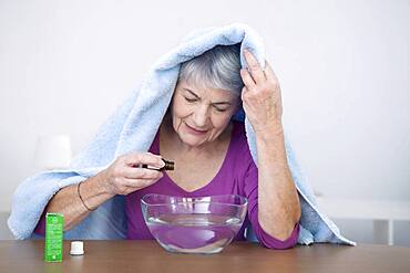 Senior woman preparing inhalation with essential oil.